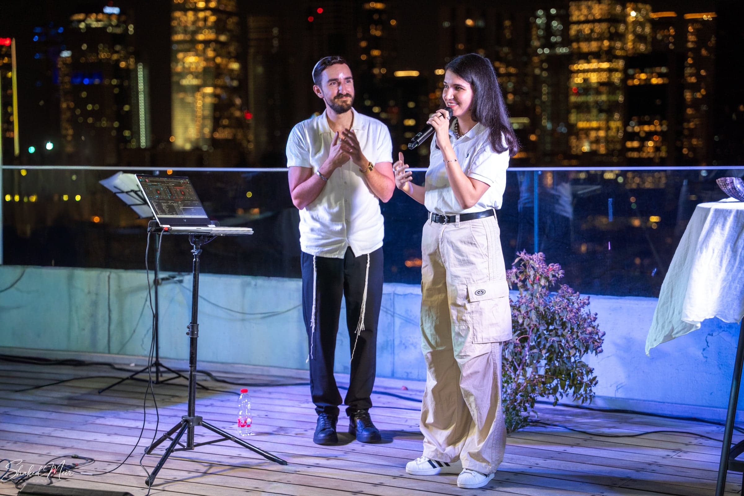 שני אנשים שרים למיקרופונים באירוע ערב מול אורות העיר