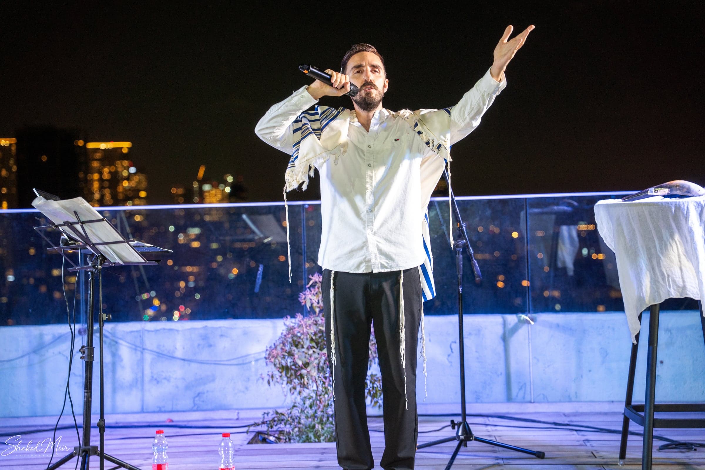 שירה מול מיקרופון במרפסת מול קו הרקיע בלילה