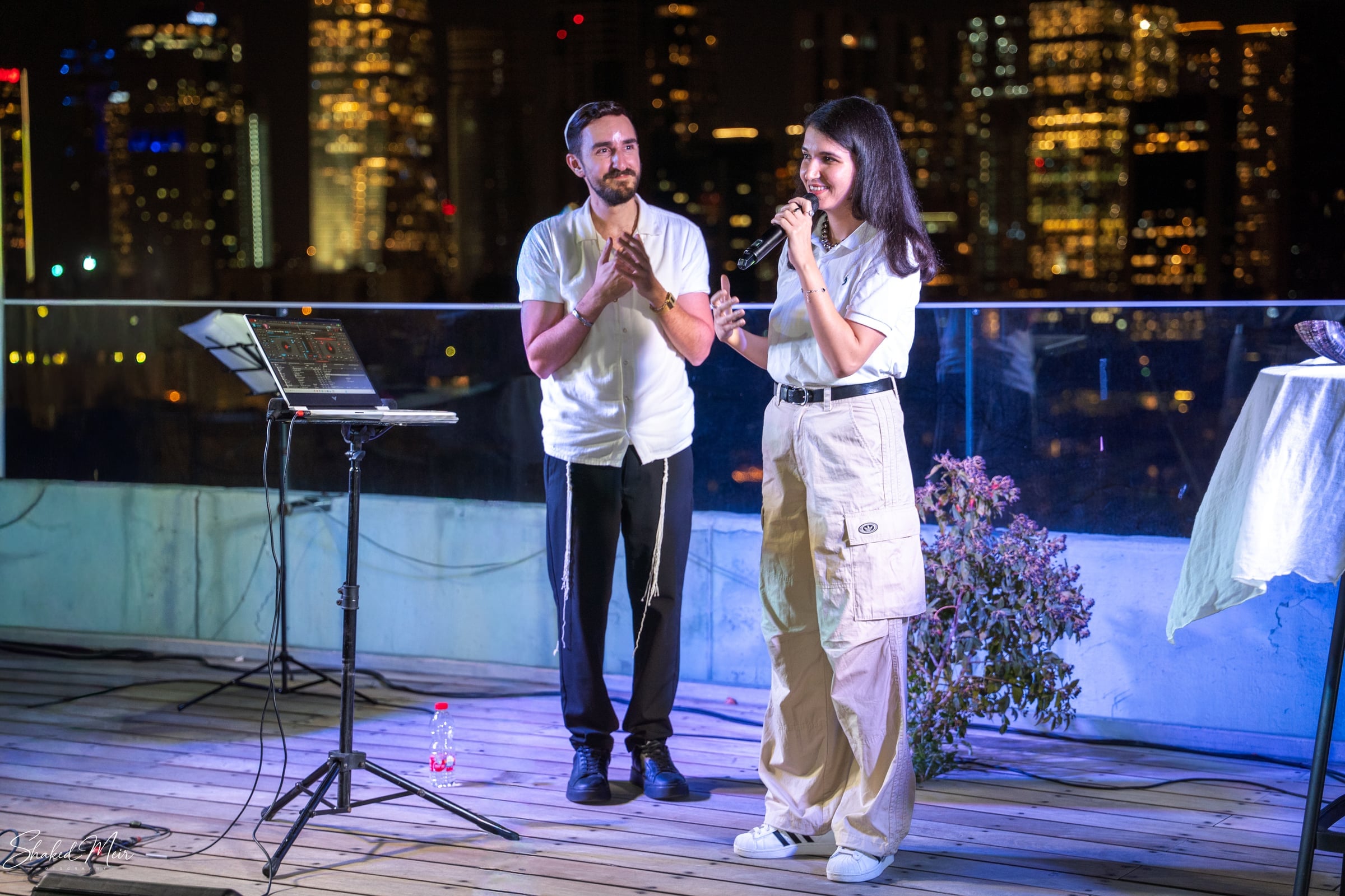 שני אנשים שרים למיקרופונים באירוע ערב מול אורות העיר
